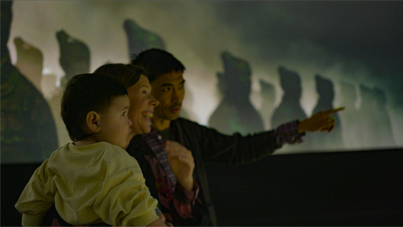 Young family stands in the opening immersive experience of Terracotta Warriors: Legacy of the First Emperor.
