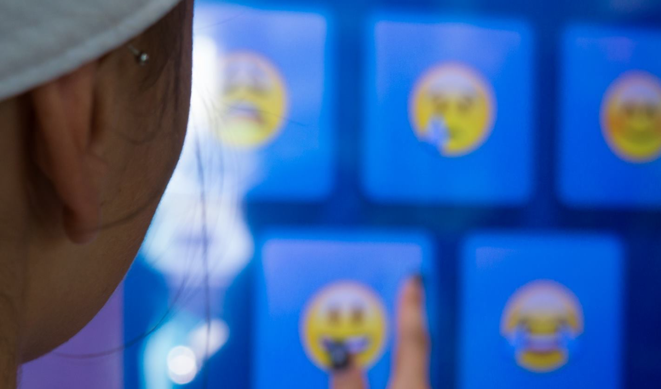 Woman interacts with emojis on an event kiosk screen as part of Blackmores Well Bot artificial intelligence chatbot.