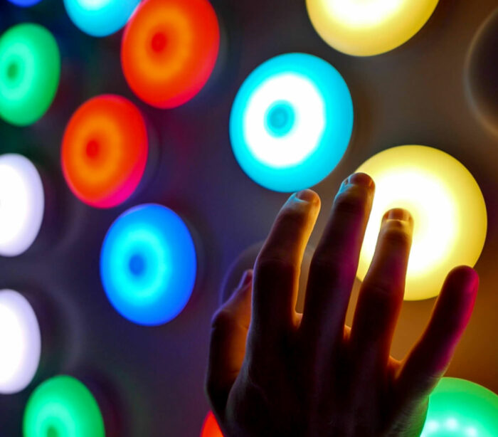 Close up of person using their hand to interact with colourful, circular LED lights from Canberra Centre touch wall light installation.