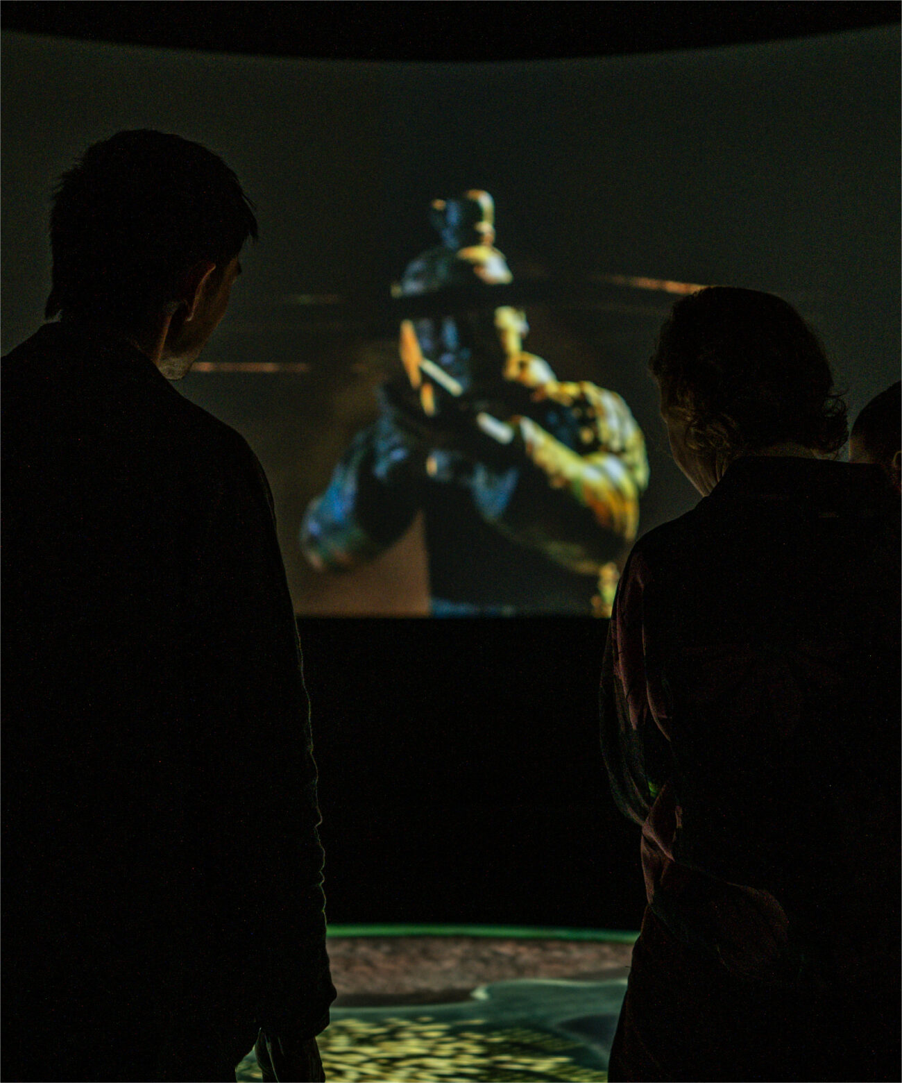 Man and woman stand facing Terracotta Warrior on wraparound projection mapping experience for Western Australia Museum.