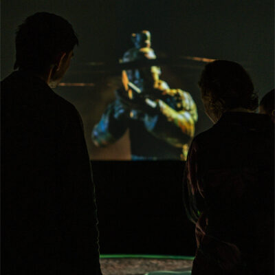 Man and woman stand facing Terracotta Warrior on wraparound projection mapping experience for Western Australia Museum.