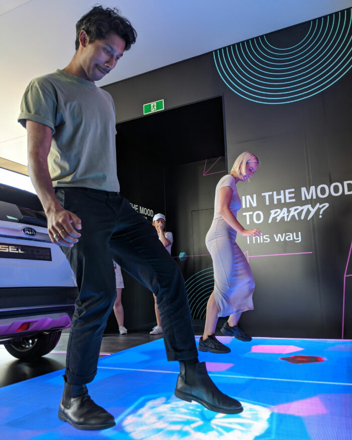 Man and woman use their feet on interactive LED dance floor of Kia Beat the Beat.