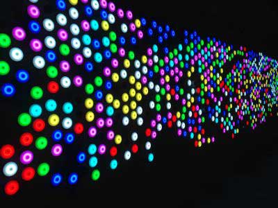 Multi-coloured LED lights in custom-built circular silicone fixtures line a wall at the Canberra Centre light touch wall as part of an interactive artwork.