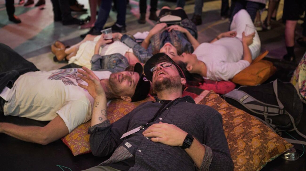 Audiences at Fables From The Threshold exhibition lie on the ground to look at an interactive artwork.