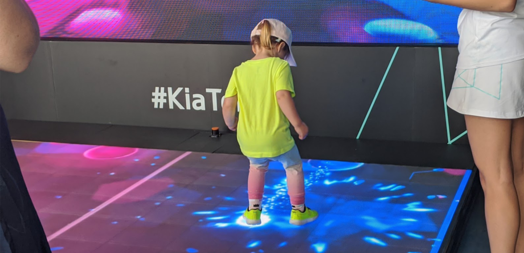 Small child interacts with LED floor of Kia Beat the Beat at the Australian Open.