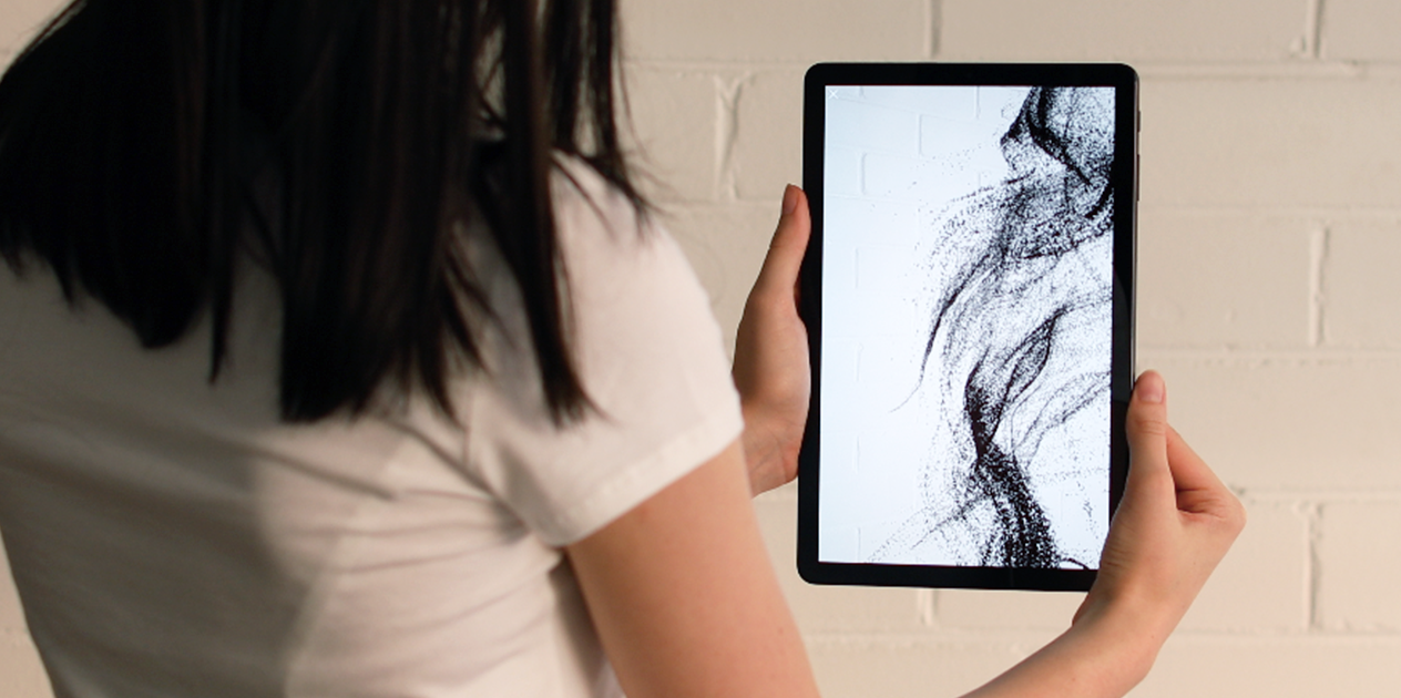 Woman holds tablet with Nespresso Vertuo AR particle visualisation.