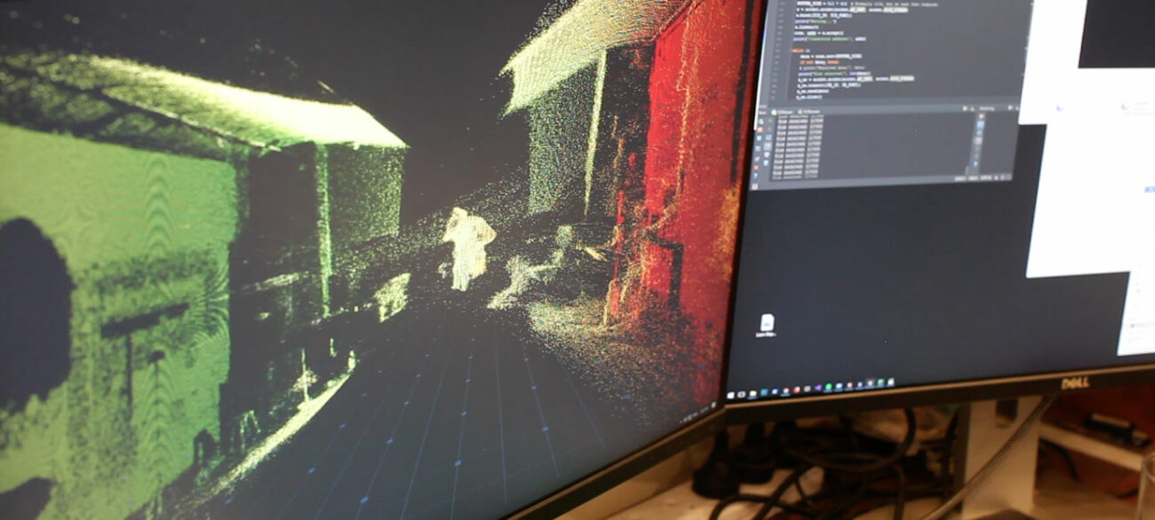 Two screens show the programming and point cloud render during production for virtual reality research into 3D scene reconstruction.