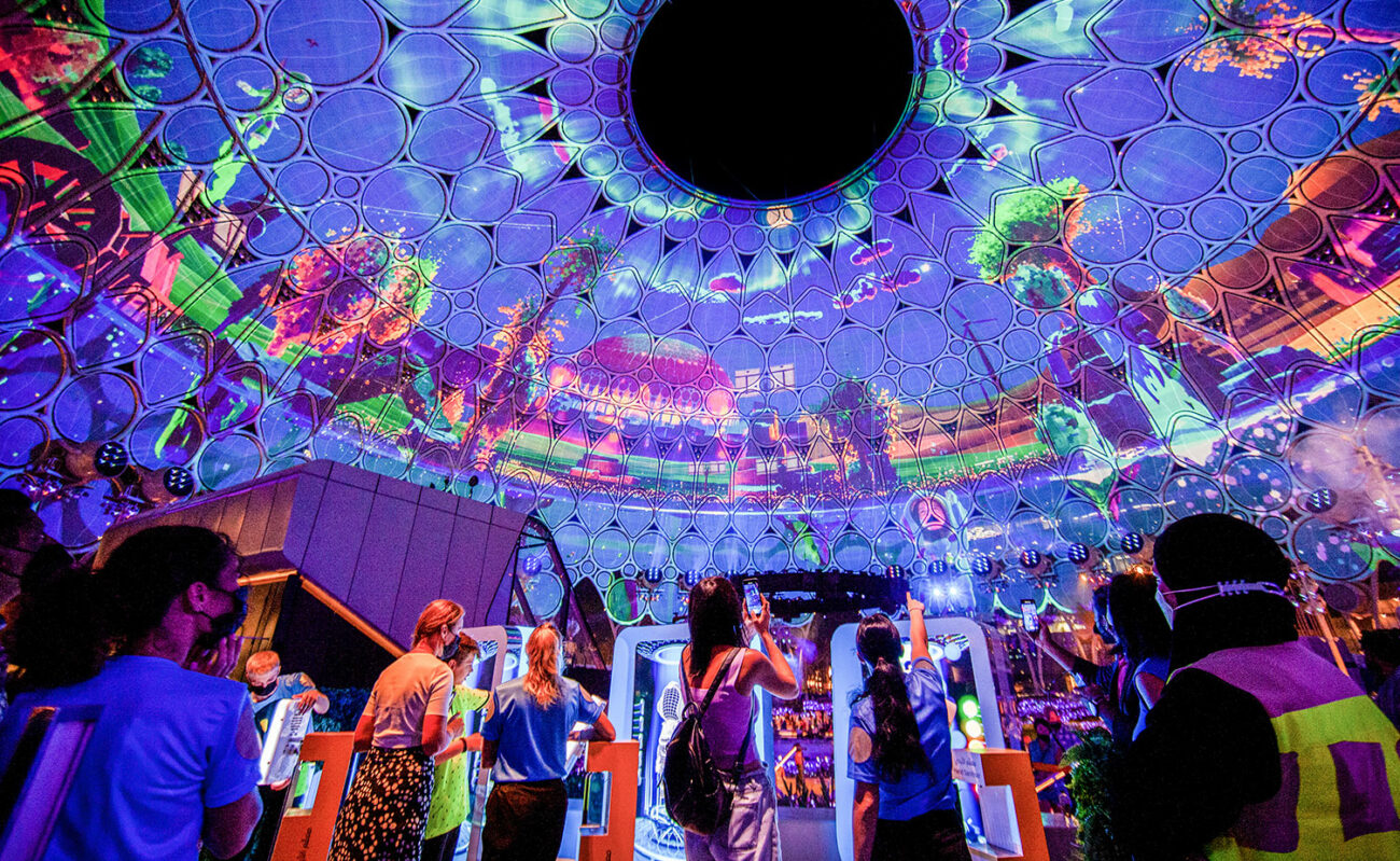 Crowd of visitors to Dubai World Expo look up at the huge immersive projection from creative studio S1T2.