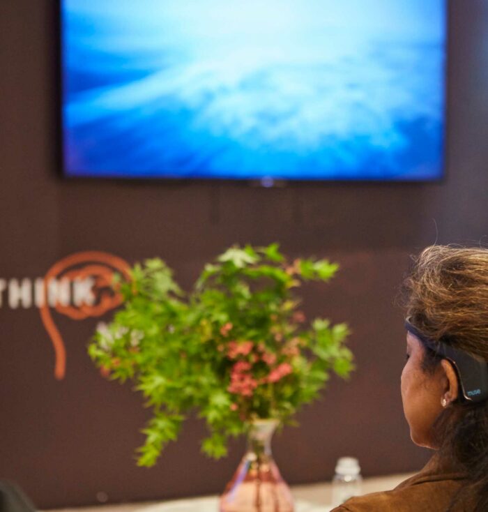 Women wears an EEG sensor, whose data is used to control a real-time data visualisation in AIA Thinkwell.