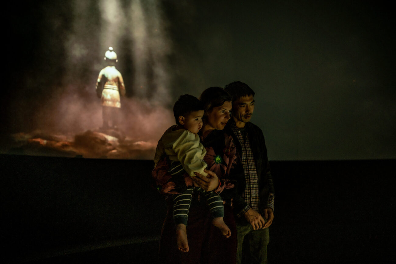 Young family stands in front of real-time immersive projection mapping display of Terracotta Warriors.