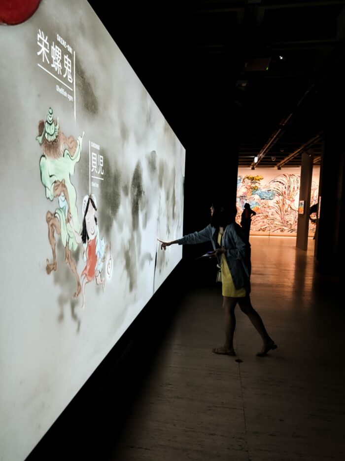 Woman use her hand to trigger an interaction point for projection animations at Japan Supernatural.