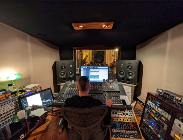 Sound designer sits before a large sound board in a recording studio during development of the soundscapes for ‘Tyama’ exhibition Melbourne Museum.