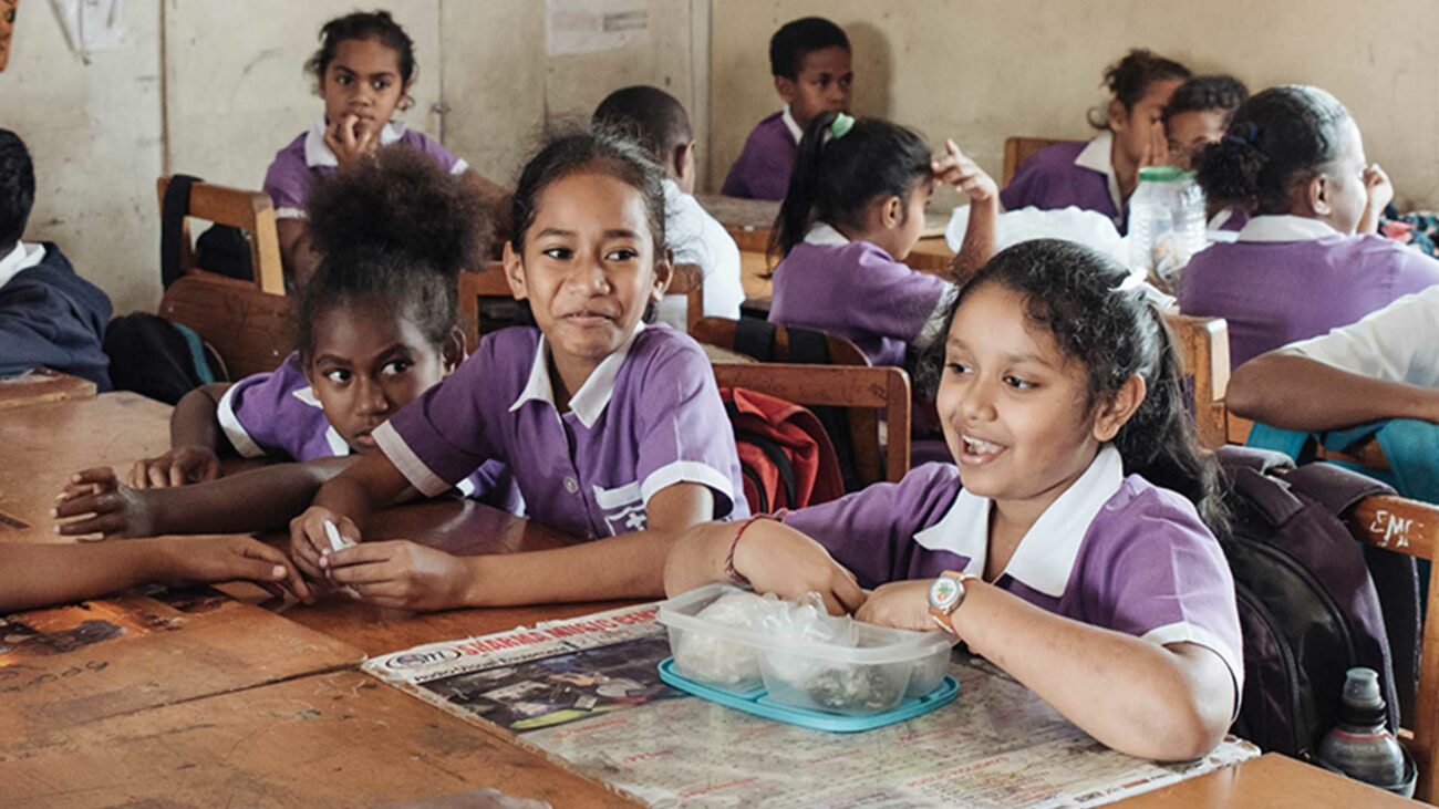 Children in Fiji eat lunch in a classroom.