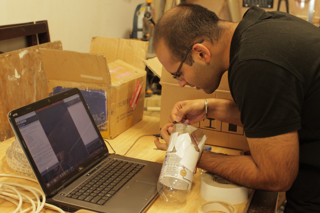 Man using soldering iron behind laptop.