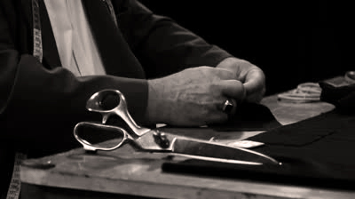 Close up of a tailor sewing a button.